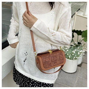 Detail of vintage brown floral embossed crossbody bag with gold metallic lock closure