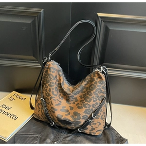 Detail of leopard print canvas bag with black straps on leather jacket background