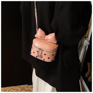 Detailed view of a pink polka dot mini bag with a large bow and metallic chain strap