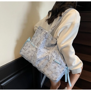 Vue détaillée du grand sac cabas gris à motif marbre avec ruban bleu clair sur un escalier