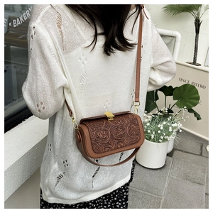 Detail of floral embossed texture on vintage brown crossbody bag with gold buckle