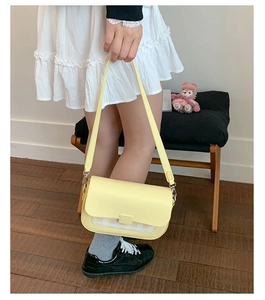 Détail d'un sac à bandoulière jaune clair en cuir avec motif à carreaux et boucles