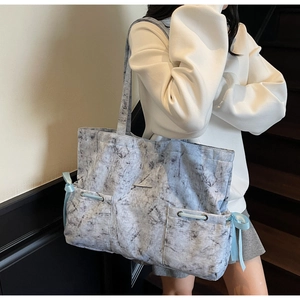 Détail du grand sac cabas à motif marbre avec poches latérales et nœuds en ruban bleu