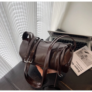 Detailed view of dark brown glossy leather cylinder bag with silver metal buckles