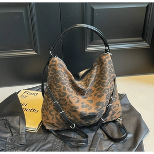 Detail of hobo bag featuring leopard print canvas with black leather handle and logo