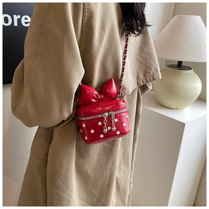 Mini crossbody bag with red polka dot pattern and oversized bow on silver chain