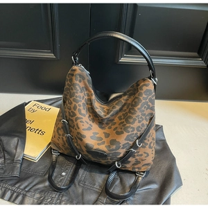 Detail of leopard print canvas hobo bag with black leather handles and silver hardware