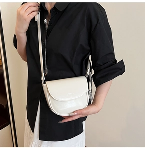 Détail du sac selle blanc crème avec texture lisse et pendentif en forme d'arachide