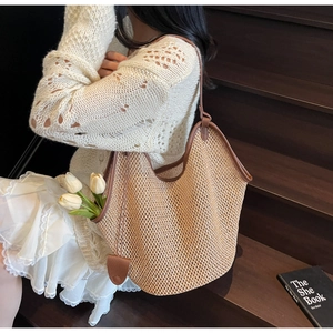 Detail of a large straw tote bag with brown leather handles and a woven texture
