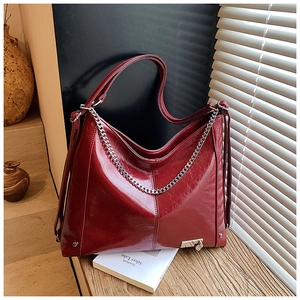 Detail of burgundy wax leather tote showing silver chain and glossy wrinkled texture