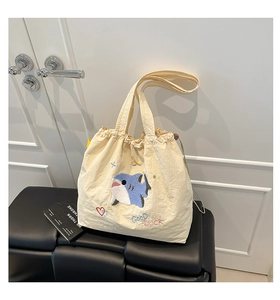 Detail der süßen Hai-Stickerei und GOOD LUCK Schriftzug auf cremefarbener Tasche