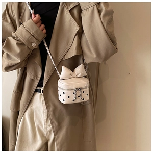 Detailed view of mini crossbody bag with large bow detail and black polka dot pattern