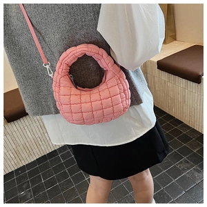 Pink quilted shoulder bag shown on model highlighting soft texture and puffy design