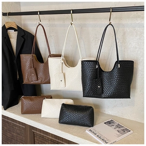 Détail de l'ensemble de sacs cabas et pochettes tressés en noir, crème et marron chic