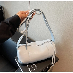 Detail of light blue cylinder bag featuring wide shoulder strap and long zipper puller