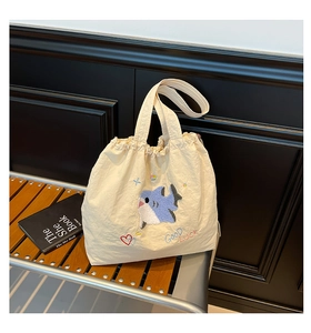 Detail der Hai-Stickerei und Good Luck Schriftzug auf cremefarbener Segeltuchtasche