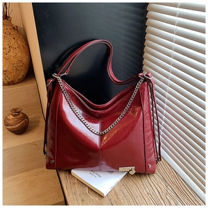 Detail of red leather tote bag with silver chain decoration and heart pendant accessory