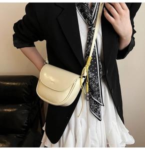Détail d'un sac besace blanc crème en cuir lisse avec un nœud décoratif jaune élégant
