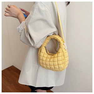 Close-up of bright yellow quilted hobo bag with padded texture and silver metal zipper