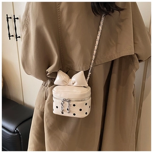 Polka dot mini crossbody bag with a large bow detail worn with a trench coat