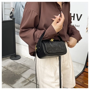Detail of vintage black box bag featuring embossed rose patterns and a gold turn-lock