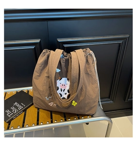 Detailaufnahme der karamellfarbenen Nylontasche mit Kuh-Stickerei und Kordelzugverschluss