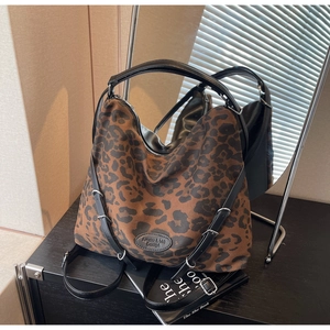 Close-up of leopard print tote bag with adjustable black strap and round leather logo