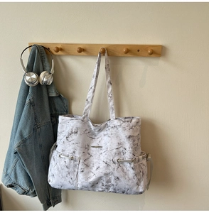 Détail du sac cabas en toile avec motif marbre et deux poches avant à oeillets métalliques
