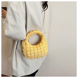 Detail of yellow quilted puffer shoulder bag showing fluffy texture and fine stitching
