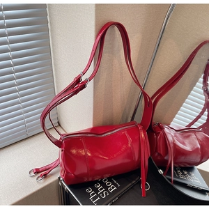 Macro detail of red cylindrical leather bag featuring silver zipper and long fringe tassel