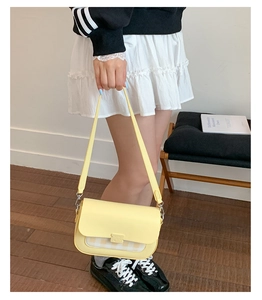 Détail du sac à rabat en cuir jaune clair avec tissu à carreaux jaune-blanc et fermoir chic