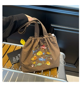 Detailansicht der braunen Nylon-Tasche mit bunter Fisch-Stickerei und Kordelzugverschluss