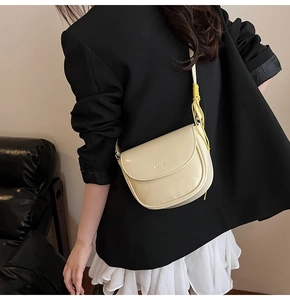 Détail d'un sac besace beige avec une corde nouée jaune sur la bandoulière réglable