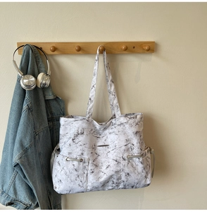 Détail du cabas en toile à motif marbre avec poches fonctionnelles et boucles argentées