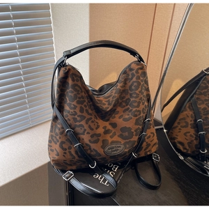 Detail of the leopard print canvas hobo bag with black leather logo patch and strap