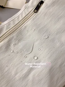 Nahaufnahme des wasserabweisenden Nylongewebes mit Tropfendetails an der beigen Umhängetasche
