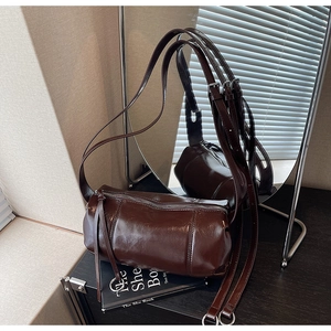 Detail of deep brown oil wax leather texture and silver zipper on cylindrical bag