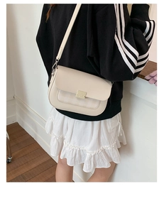Détail du sac bandoulière blanc crème avec fermoir argenté et rabat à carreaux texturé