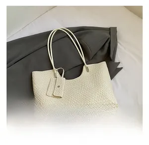 Détail du sac cabas tressé minimaliste avec pochette assortie et finitions argentées