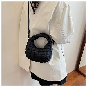 Chic black quilted puffer bag shown on a model with adjustable strap and top handle