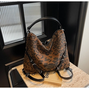 Detailed close-up of leopard print backpack with black leather straps and brand logo
