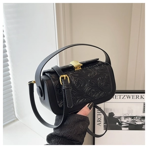 Close-up of black vintage handbag with 3D floral embossing and gold metal clasp hardware