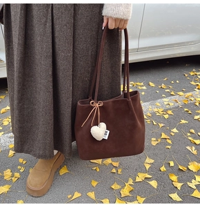 Macro shot of dark brown suede tote bag with a white plush heart charm and bow detail