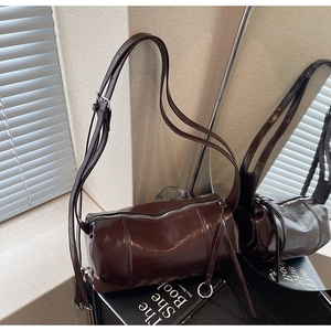 Macro shot of dark coffee barrel bag with glossy leather texture and silver hardware