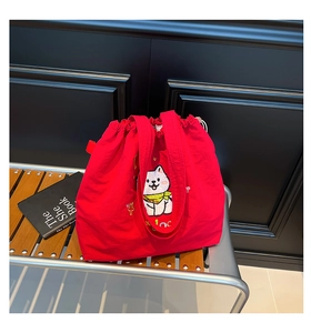Detail der roten Segeltuchtasche mit süßer weißer Cartoon-Hundestickerei und Kordelzugverschluss
