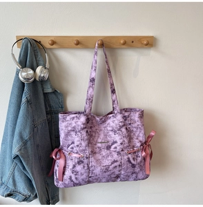 Sac cabas violet tie-dye avec nœuds en satin rose et logo en métal sur un crochet