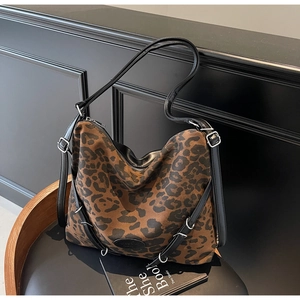 Detailed view of leopard print tote bag featuring black leather strap and silver buckle
