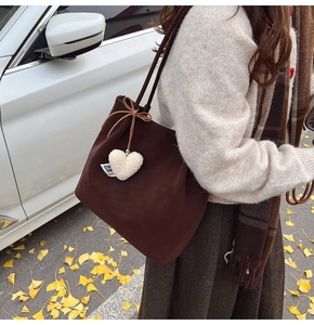 Detail of vintage brown frosted tote bag with plush heart charm and autumn aesthetic