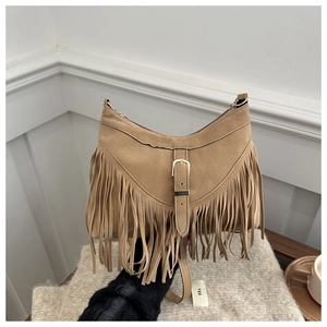 Close-up of bohemian camel suede hobo bag featuring long tassels and belt buckle detail