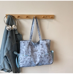 Détail du sac cabas en toile marbrée bleue avec des nœuds coulissants en ruban de soie